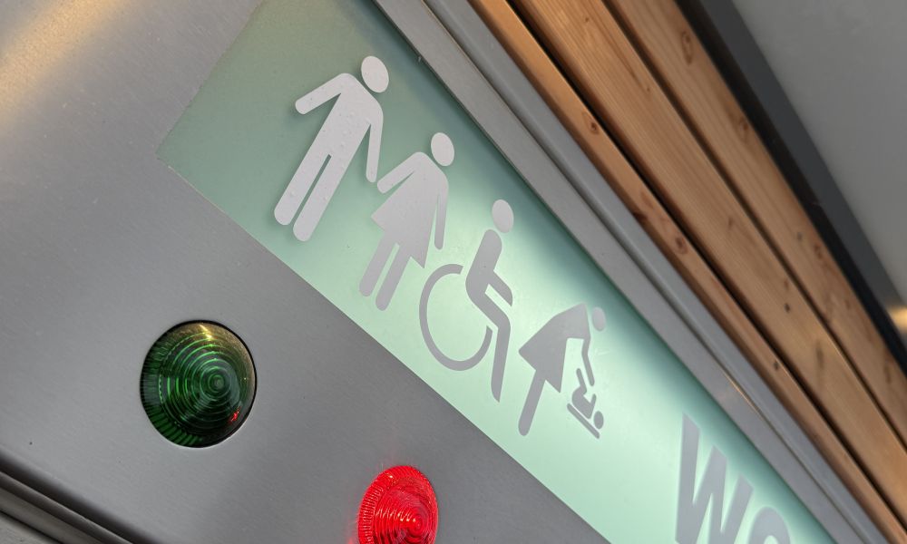 Piktogramme über der Tür zur Toilettenanlage zeigen auch die Möglichkeit des Zugangs für Gehbehinderte und der Nutzung eines Wickeltischs.