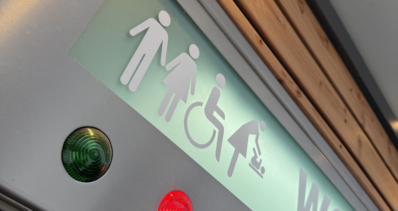 Piktogramme über der Tür zur Toilettenanlage zeigen auch die Möglichkeit des Zugangs für Gehbehinderte und der Nutzung eines Wickeltischs.